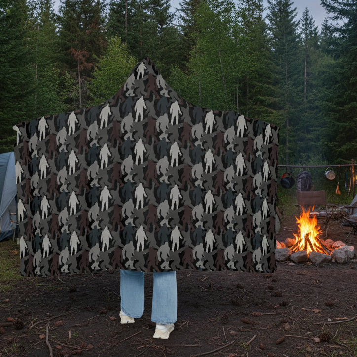 Hooded blanket with a pattern of stylized figures draped over a person on a white background